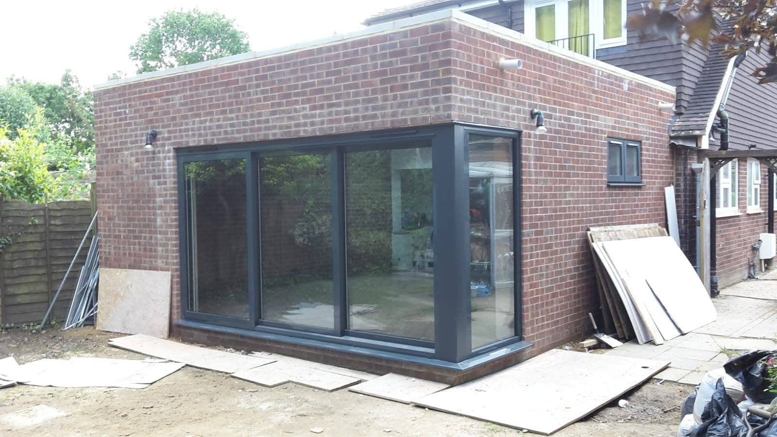 A finished single-storey extension by Trojan Construction with full-width anthracite-grey bifold doors A finished single-storey extension by Trojan Construction with full-width anthracite-grey bifold doors